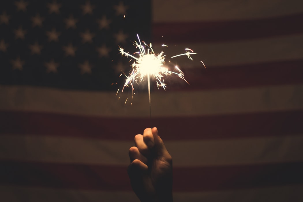 lit-sparkler-in-dark-with-american-flag-in-background