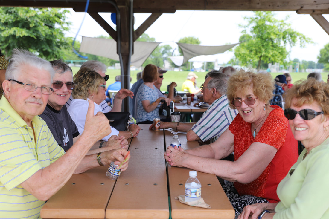 hearing aid customers smile and sit at picnic table