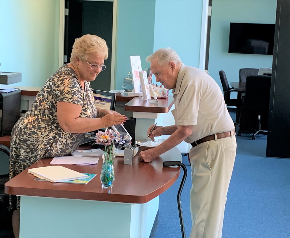 receptionist helps customer with hearing aid battery purchase at front desk