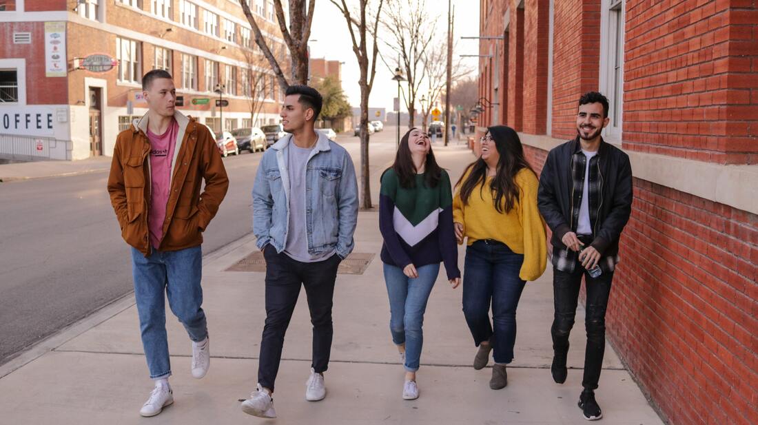 a-group-of-students-walking-and-talking-on-sidewalk