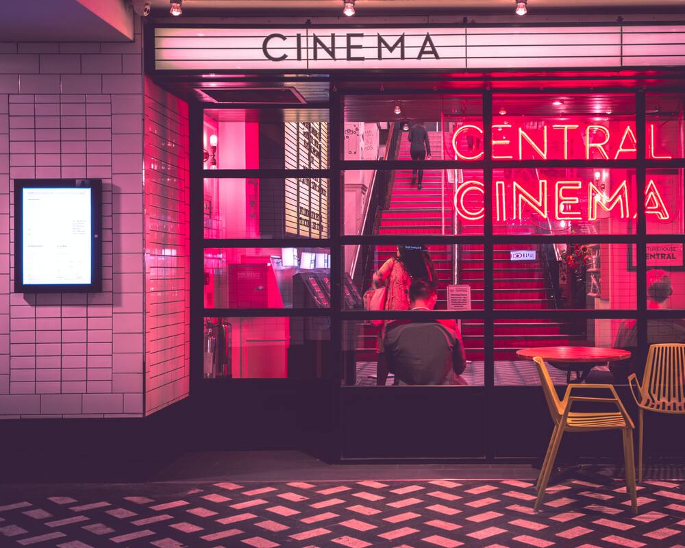 A cinema lobby with pink neon lights has movie captions in feature films.