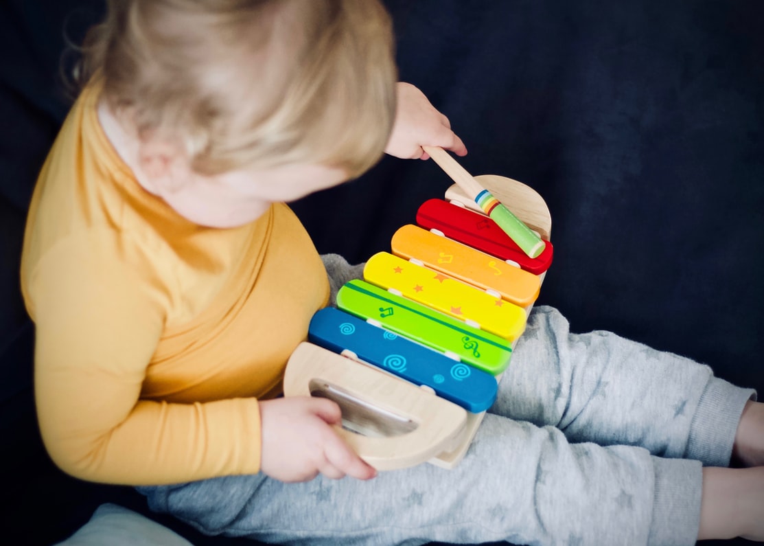 blonde haired grandchild with yellow shirt and grey pants has hearing loss after playing with loud colorful xylophone in lancaster