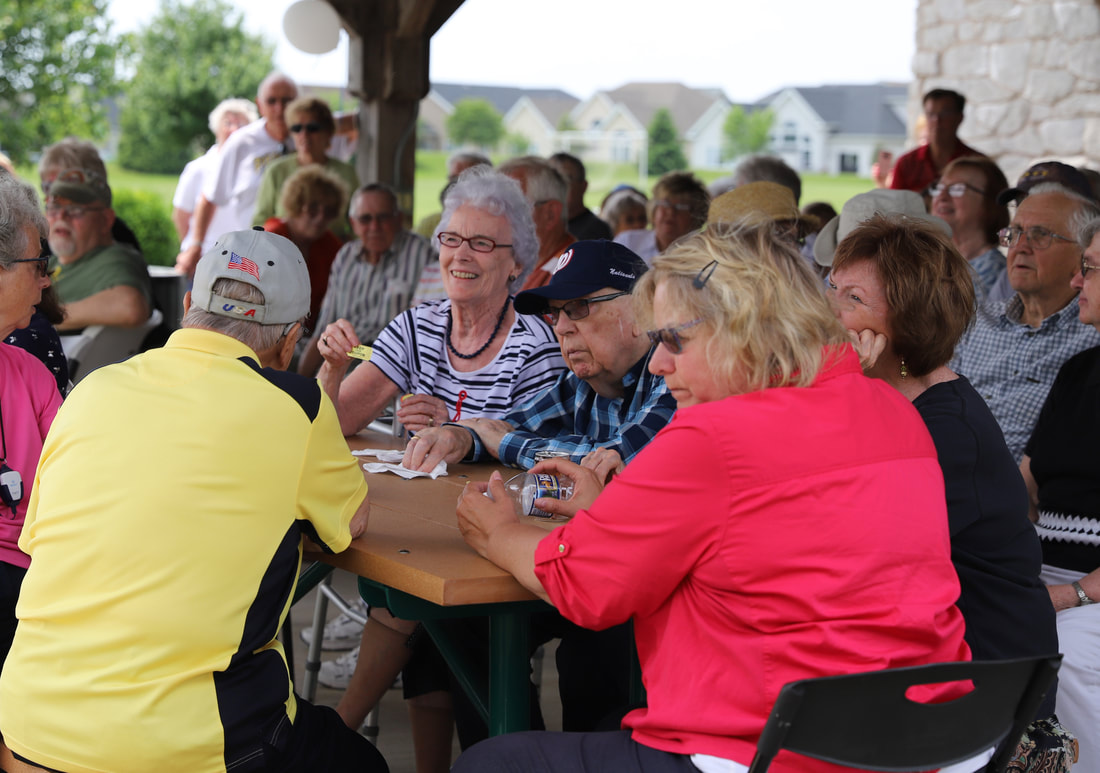customers sit and listen to raffle numbers for hearing aid customer picnic