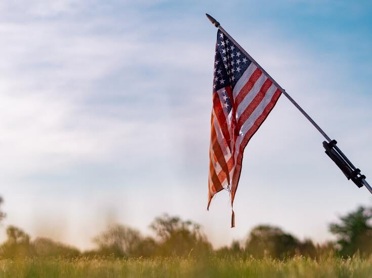 american-flag-hangs-over-green-meadow