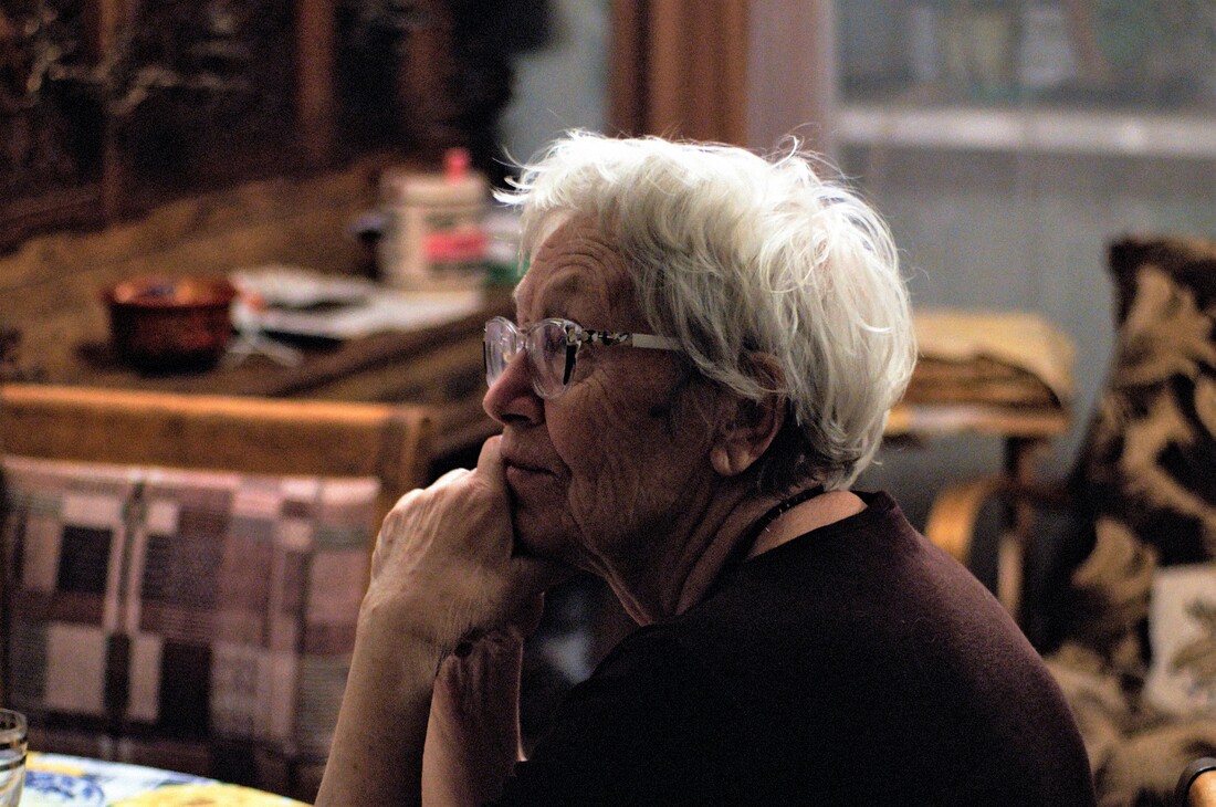 elderly woman with white hair glasses and hearing aids