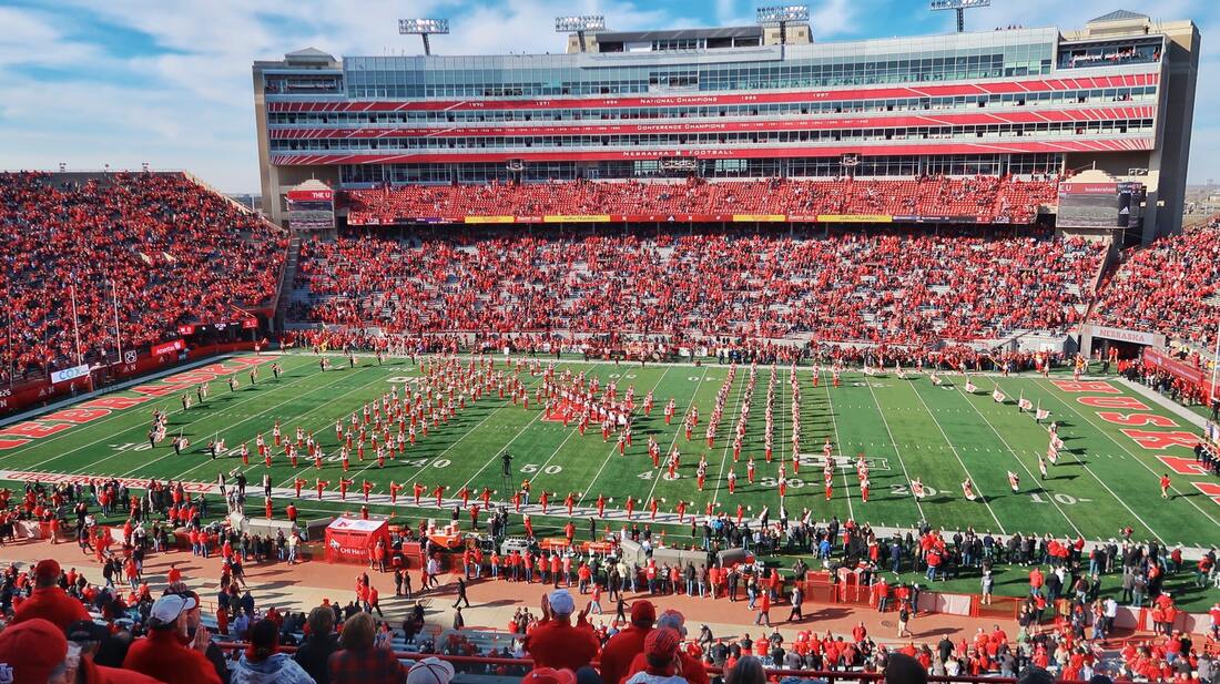 football stadium with fans in red sitting in bleachers watching half-time show