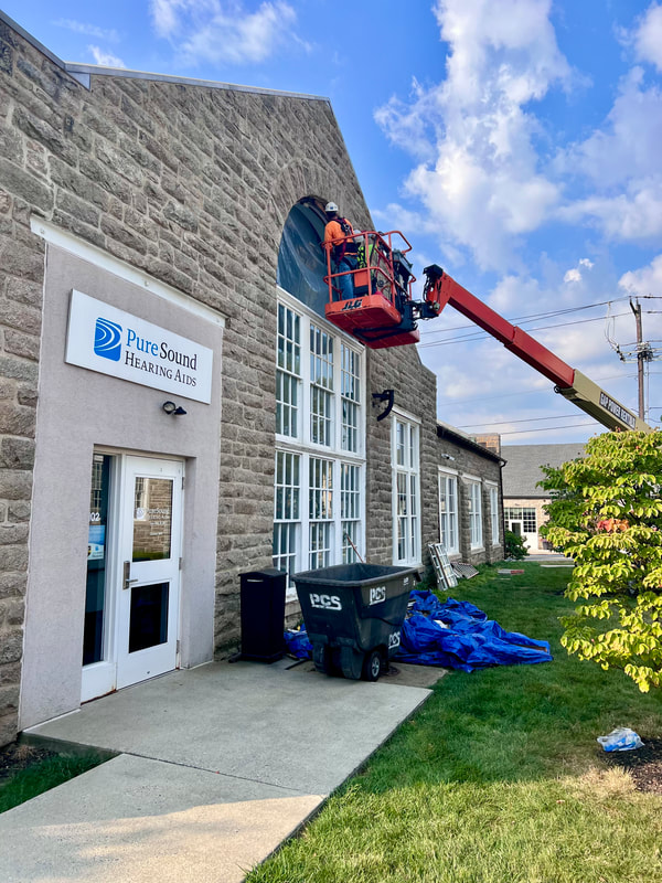 Construction workers in hard hats use a cherry picker to replace windows at a hearing aid business in Elizabethtown, PA.