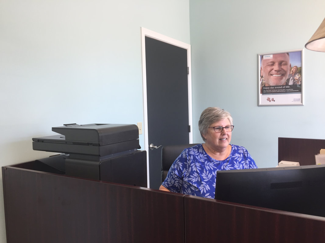 hearing aid receptionist looks at desktop computer in lititz office in lancaster pa