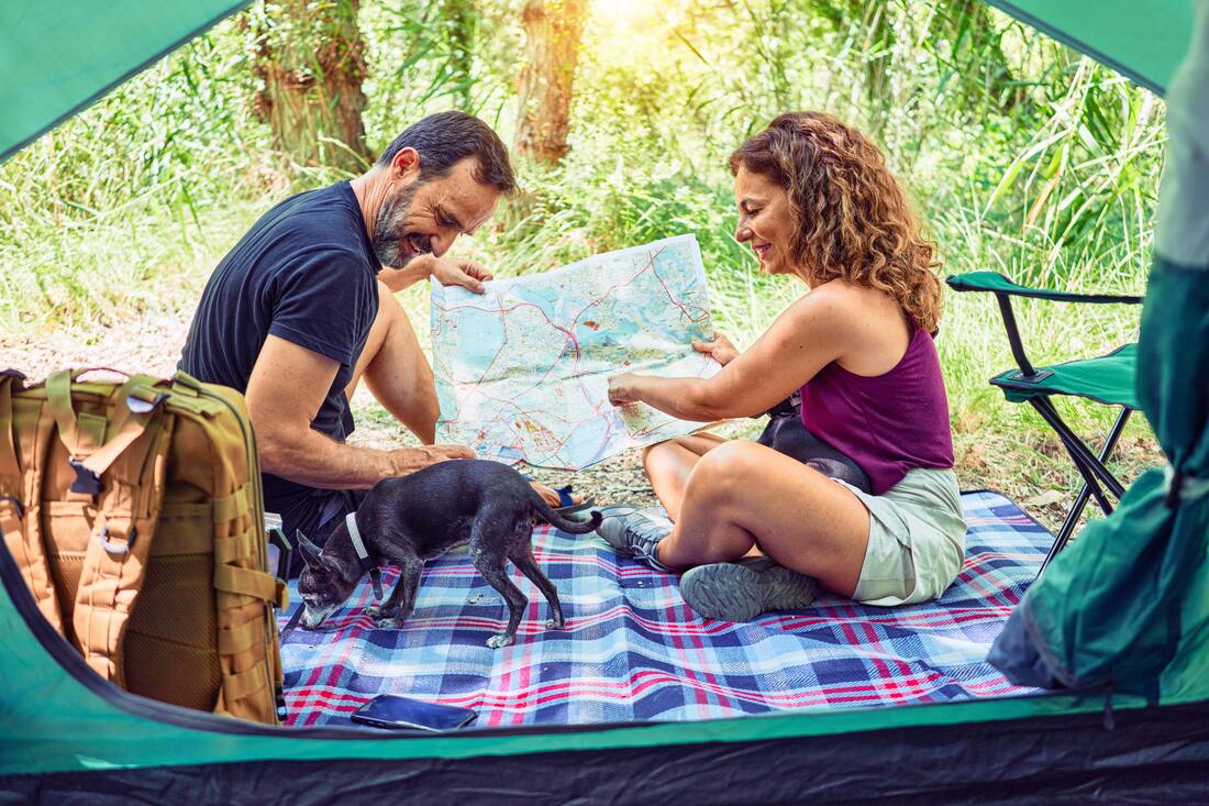 hearing_aids_for_camping_in_nature_couple_sitting_by_tent_with_map_and_dog