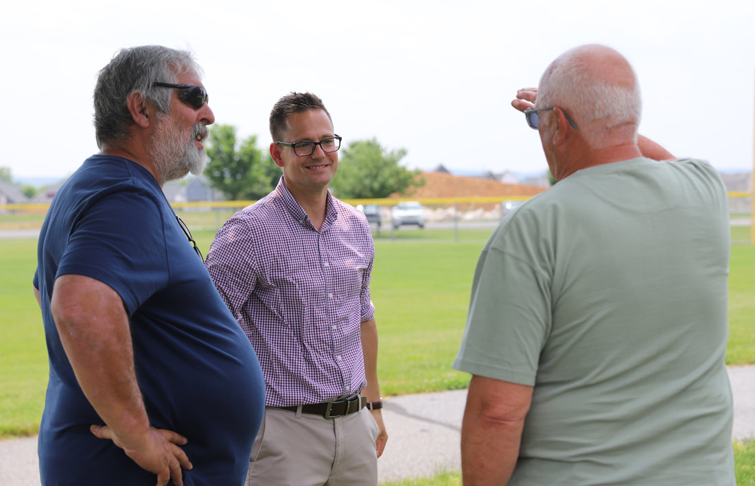 three men talk to each other at hearing aid company customer appreciation day picnic in rapho township community park in mt. joy
