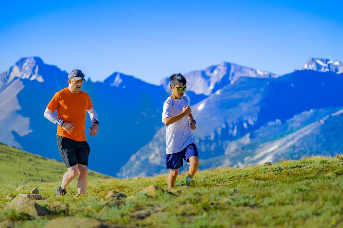 father with hearing loss jogs with son in the mountains