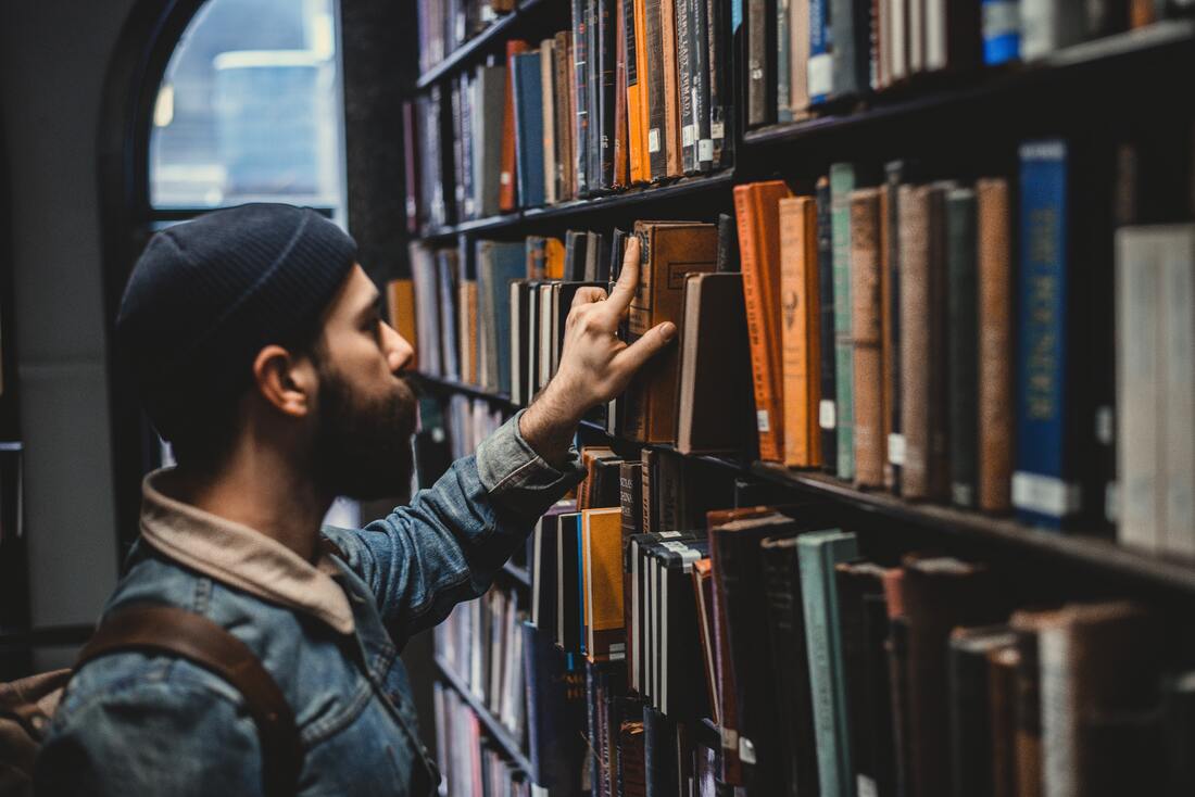 male college student looks for hearing history books in franklin and marshall college library
