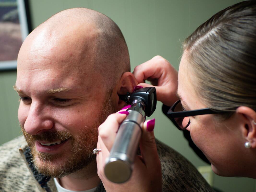 man gets ears inspected with otoscope by hearing instrument specialist