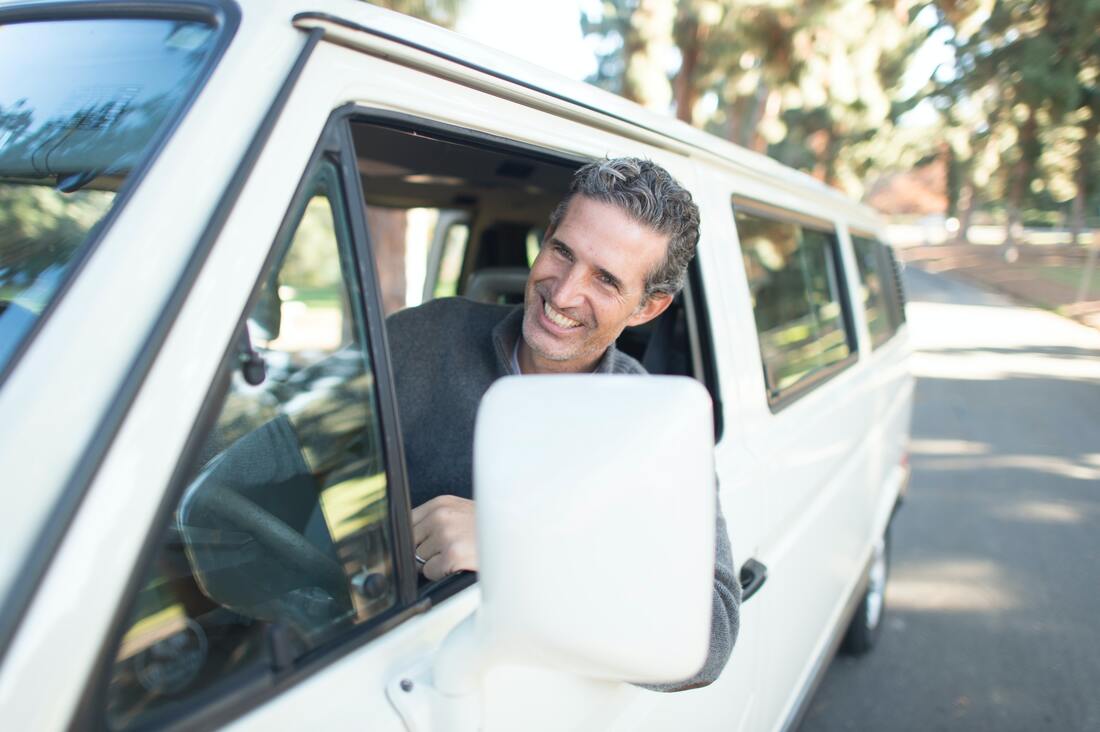 man-in-white-van-smiles-with-head-out-of-driver's-window