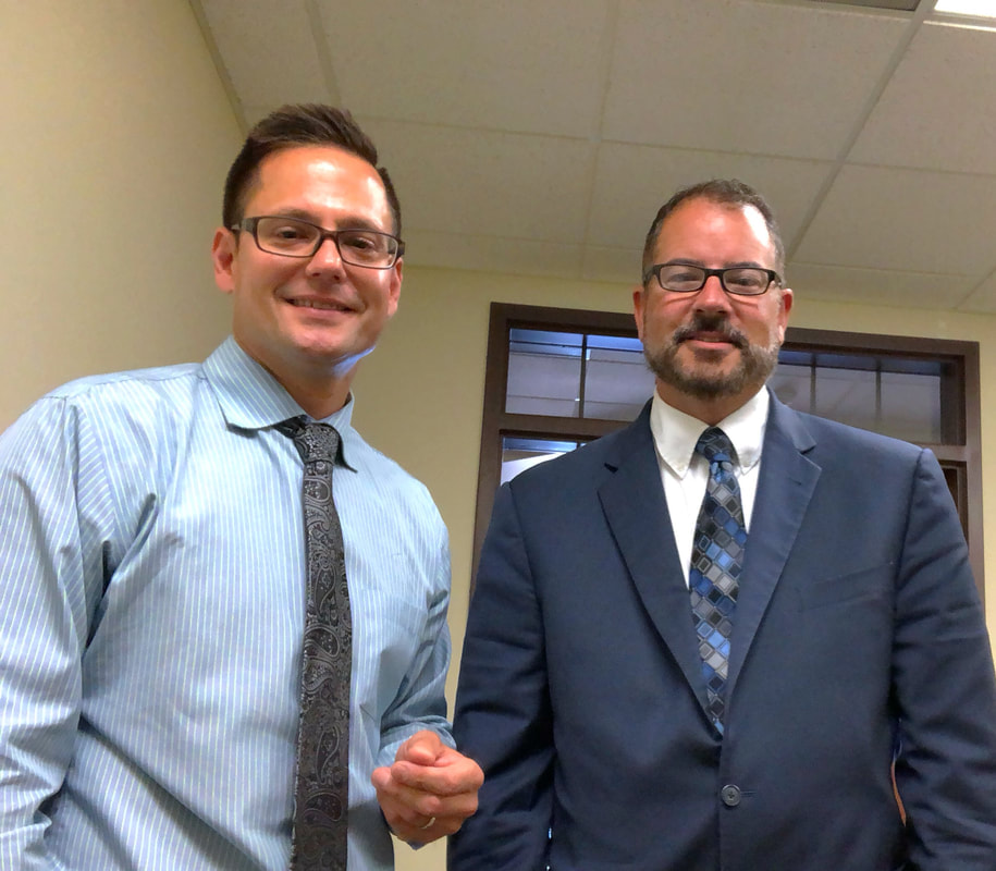 man with glasses and button down shirt with grey tie and man with glasses in suit and tie in lancaster hearing aid provider office