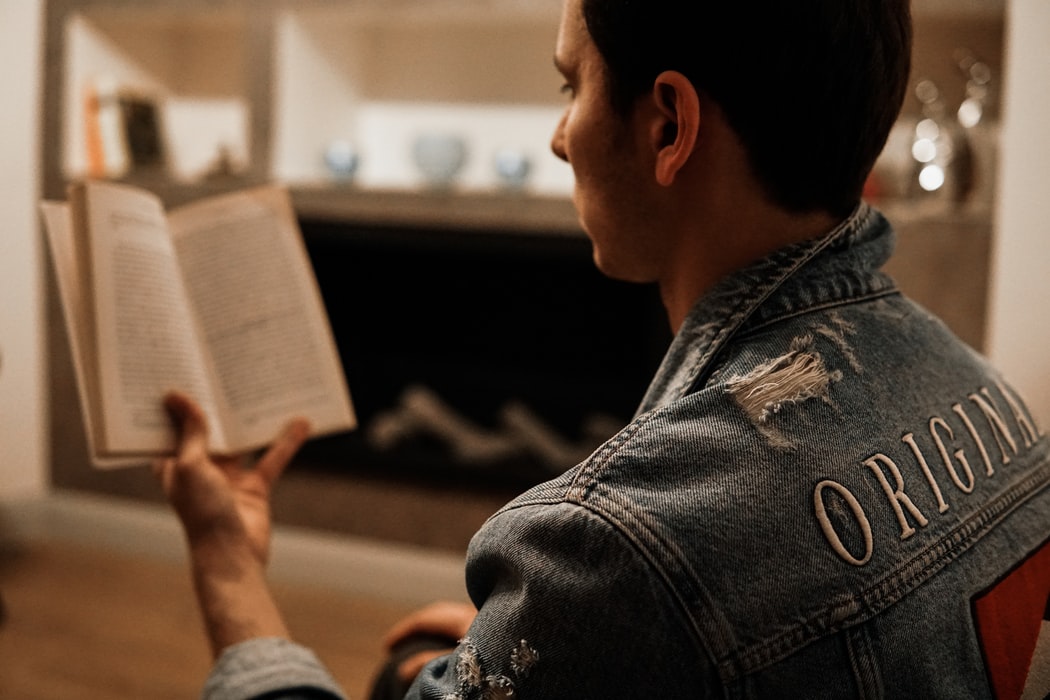 man with jean jacket and hearing aids reads out loud from book