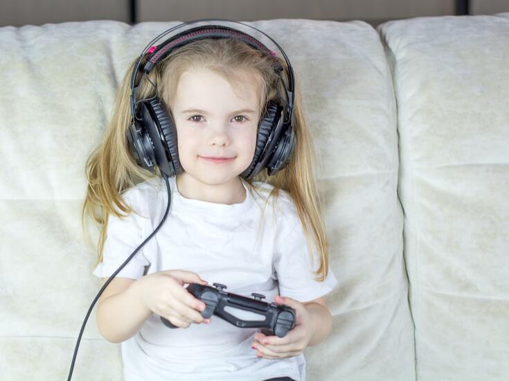 girl wears headphones and uses controller to play video game