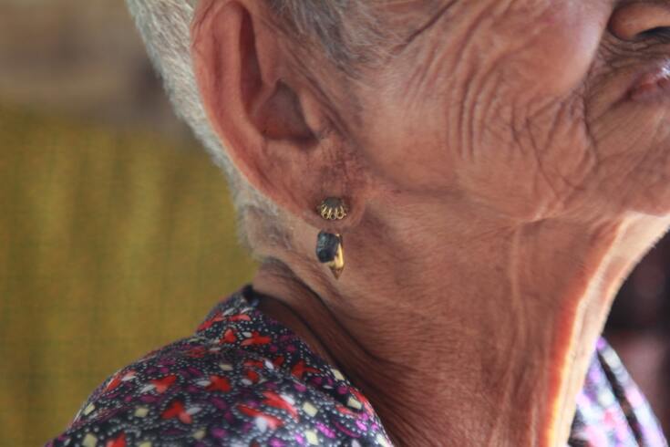 A close-up of an older woman's ear with an ear piercing.