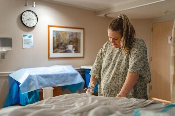 pregnant_woman_wearing_hospital_gown_clutches_to_hospital_bed_and_experiences_hearing_loss_after_giving_birth_in_UMPC_lititz