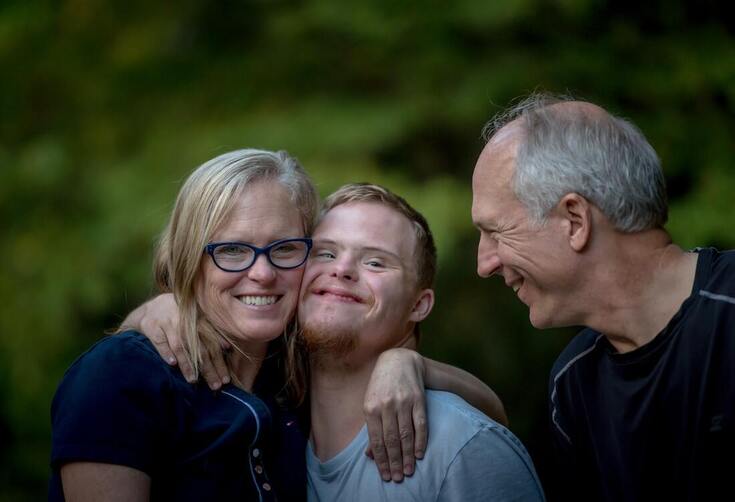 smiling parents and son with down syndrome and hearing loss