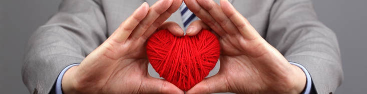 red yarn shaped as heart held by man in suit represents humanitarian efforts with hearing aids in lancaster pa