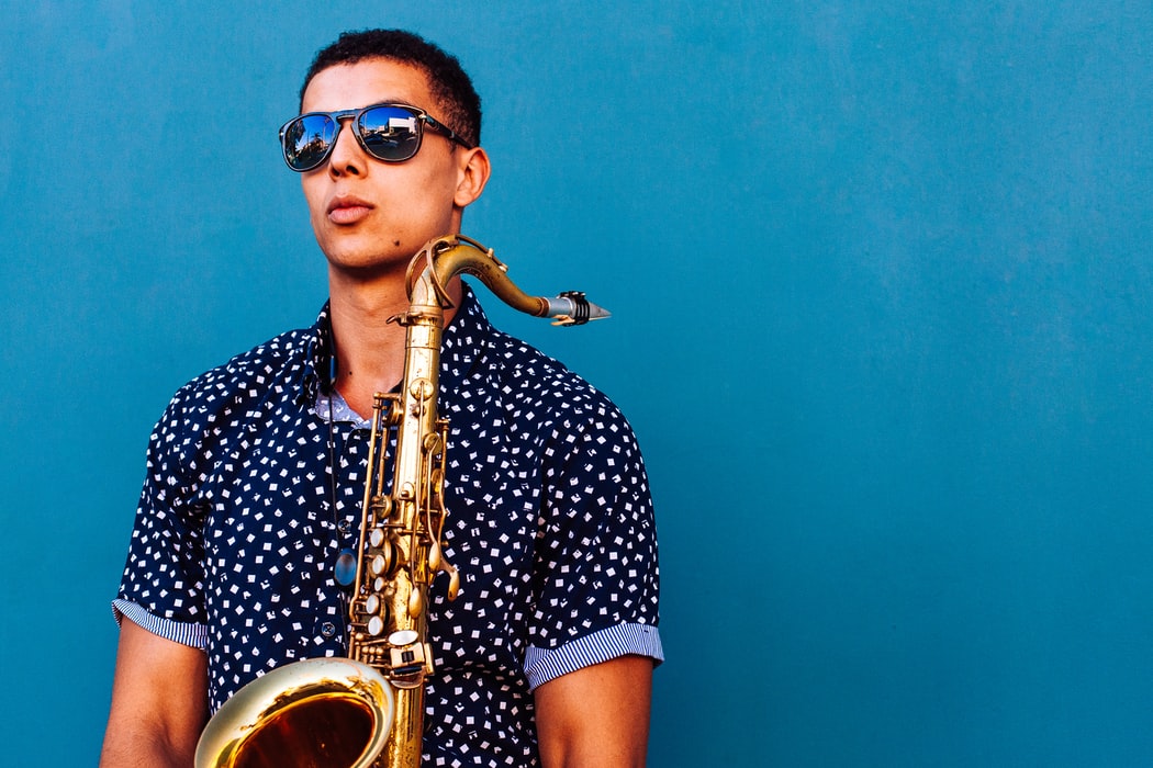 saxophonist with sunglasses wears programmed hearing aids while holding saxophone