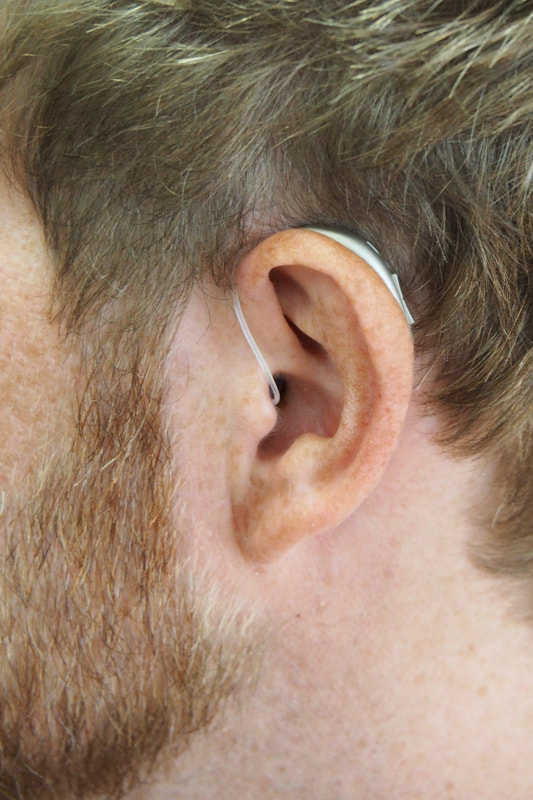 silver behind the ear hearing aid fitted in the ear of a bearded man from lititz