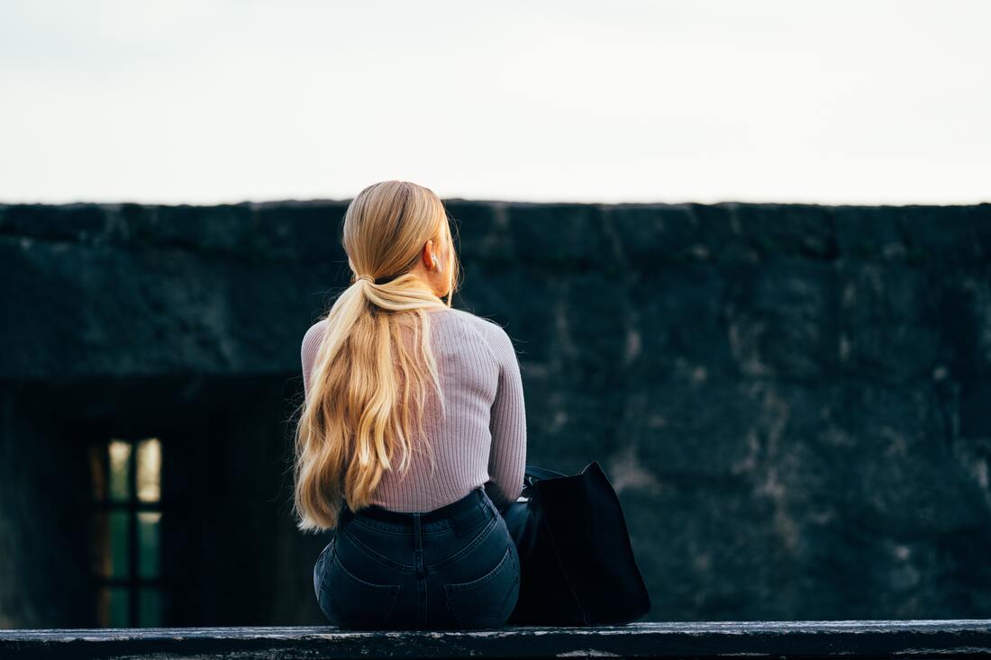 sitting_blonde_haired_woman_with_ponytail_wearing_blue_jeans_and_lavender_sweater_needs_advice_on_how_to_adjust_to_hearing_aids_from_pure_sound_hearing_in_lancaster_pa