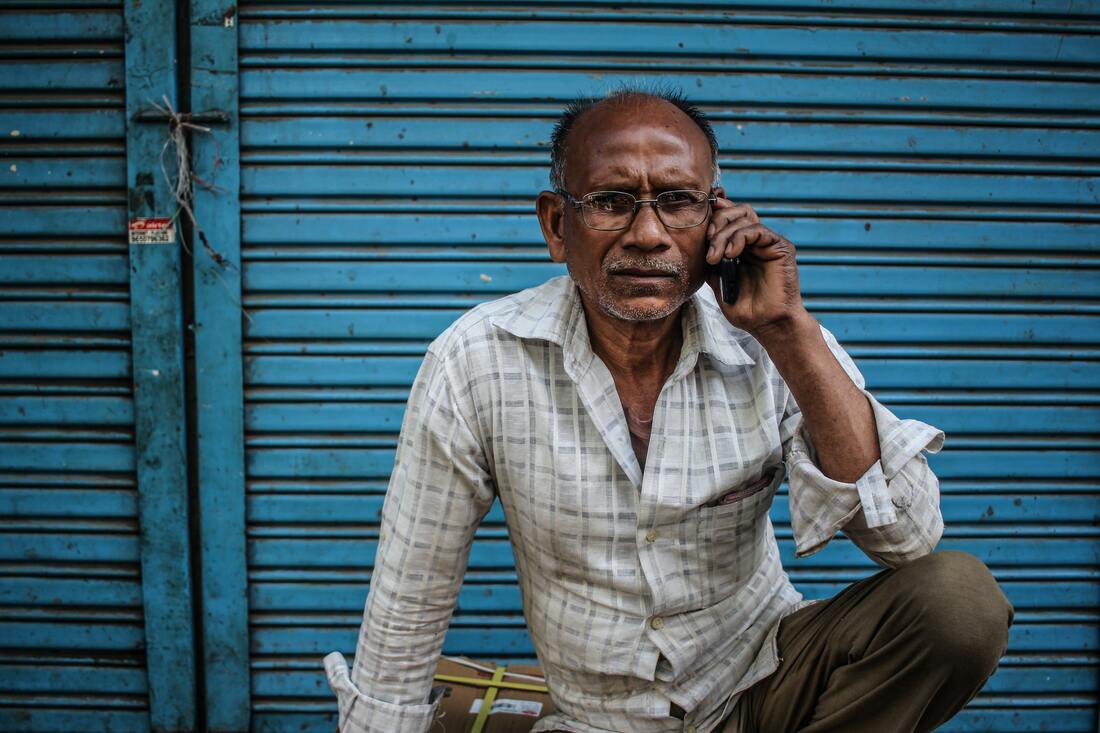 sitting man wearing grey shirt holding phone on ear