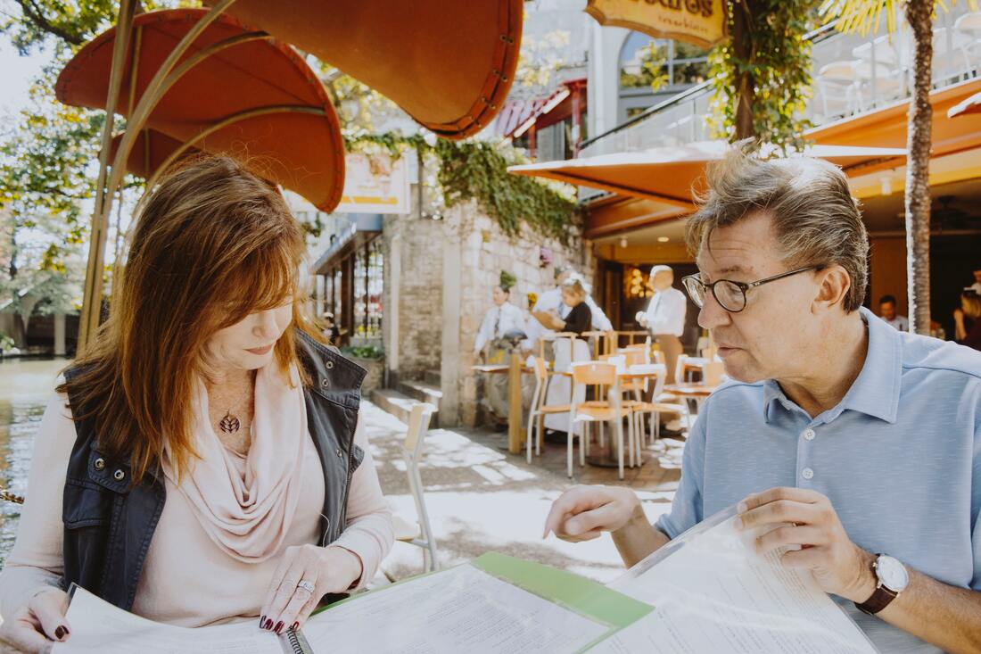 woman and man at outdoor restaurant looking at menu