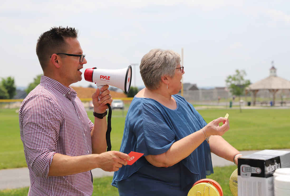 woman and man with bullhorn call out raffle numbers at hearing aid company customer appreciation day