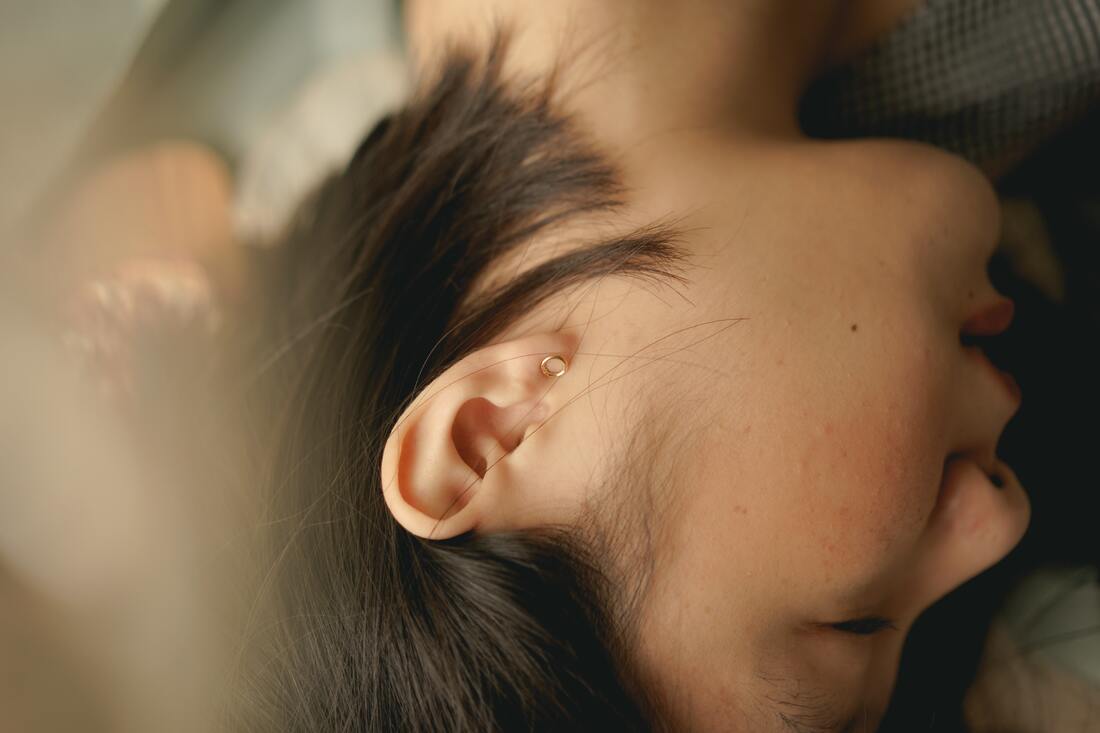 woman lies down to rest from hearing loss caused by ear infection