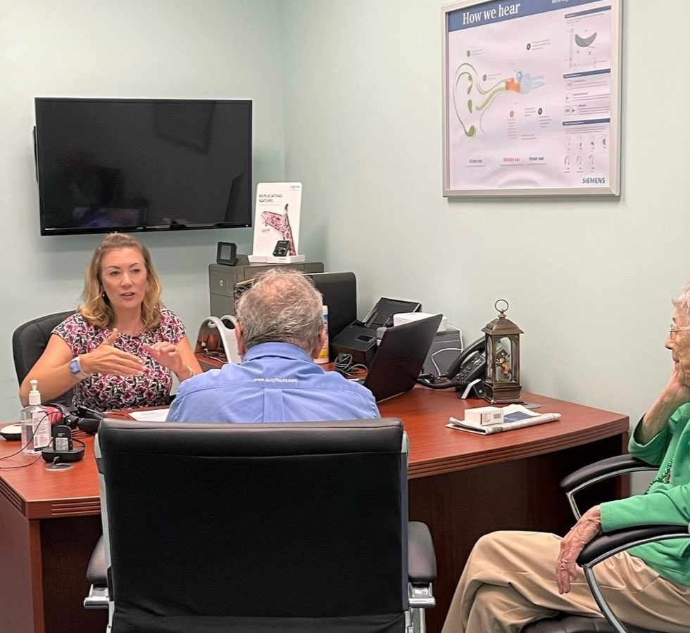 woman talks to patients about hearing aids in office