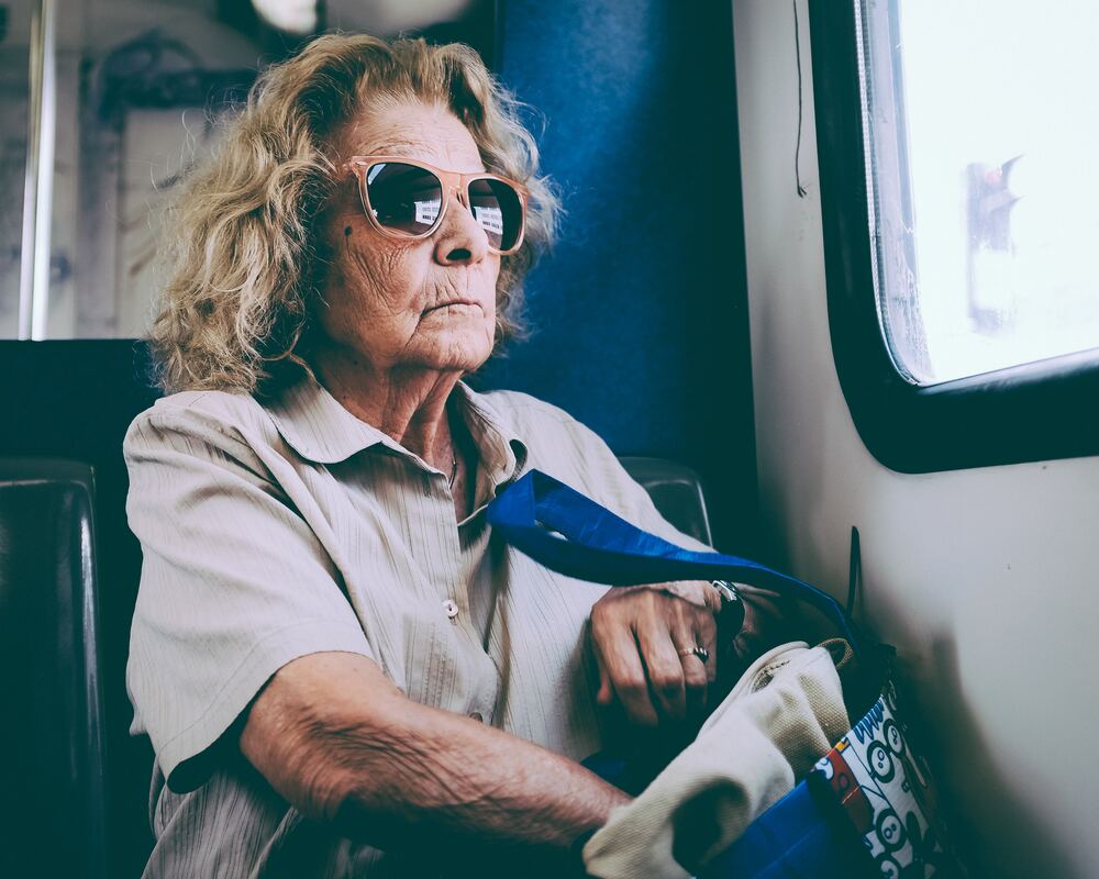 A woman with sunglasses and hearing loss travels solo via public transportation.