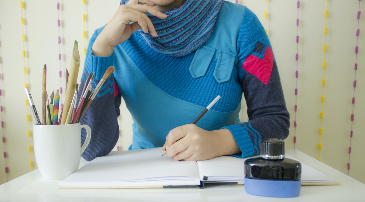 woman with blue multi patterned sweater and heart stitched in sleeve gets ready to sketch