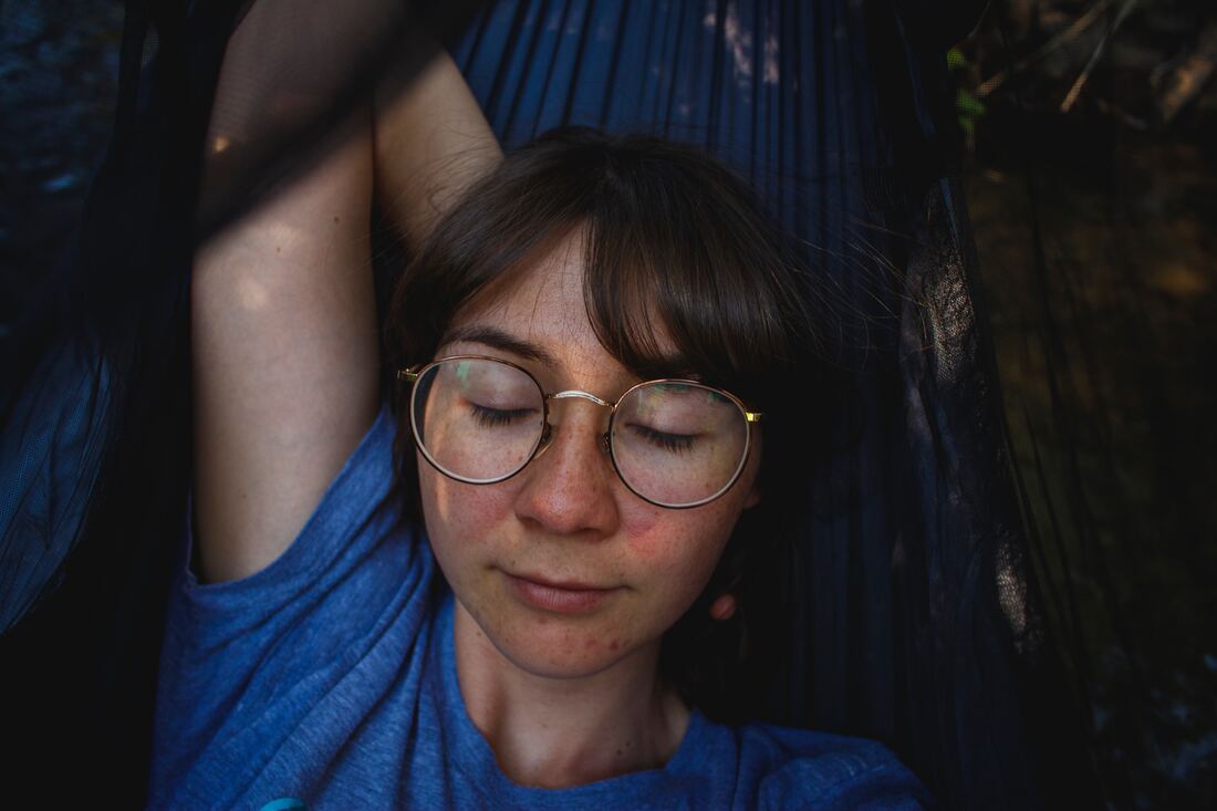 woman with glasses and tinnitus lays on hammock to relax