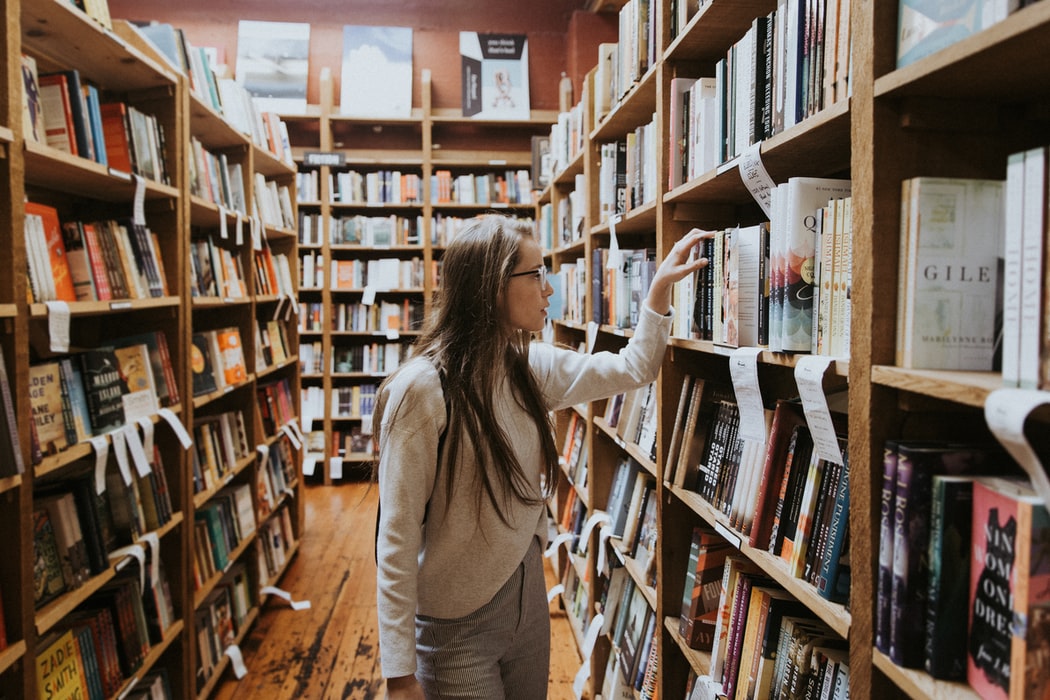 woman with hearing loss looks at books on a shelf in a bookstore
