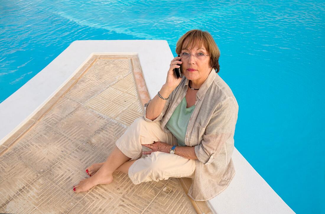 woman with hearing loss talks on smartphone by the edge of a pool in elizabethtown
